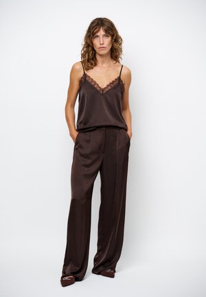 Brown satin top met kant bij de hals, gecombineerd met losse bruine broeken. De outfit heeft een strakke, gladde textuur.