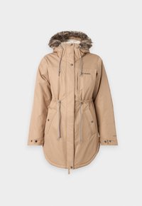 Béžová nepremokavá parka s kožušinou pod kapucňou, sťahovacím pásom, cvokmi a dvoma bočnými vreckami. Obsahuje malé logo na ľavej hrudi.