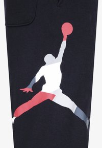 Tecido preto com um design gráfico de uma figura em salto em branco, vermelho e azul, segurando uma bola de basquete vermelha.