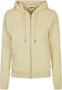Sudadera con cremallera de color amarillo claro, hecha de un tejido suave, que cuenta con capucha, cordones, bolsillos frontales y puños y dobladillo de canalé.