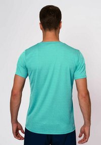 Una camisa de manga corta en color turquesa con un patrón texturizado, cuello redondo y un ajuste relajado, vista desde la parte de atrás.