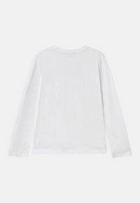 Pitkähihaisessa, pyöreäkaulaiseen T-paidassa on pehmeä, kevyt valkoinen puuvilla. Siinä on sileä pinta ja yksinkertainen muotoilu, ilman näkyviä graafisia elementtejä tai koristeita.