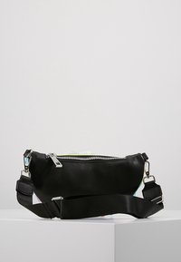 Riñonera de cuero negro con forma curva, cremallera plateada y correa de nylon ajustable. Textura suave sin patrones visibles.