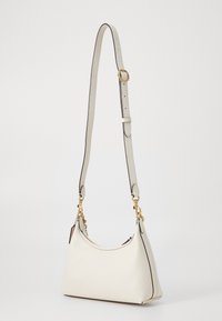 White leather handbag with a curved shape, gold hardware accents, an adjustable strap, and contrasting black trimming details.