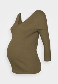 Top de maternidade de cor verde oliva e textura canelada, com um decote em V profundo e mangas três quartos, projetado para acomodar uma barriga em crescimento.