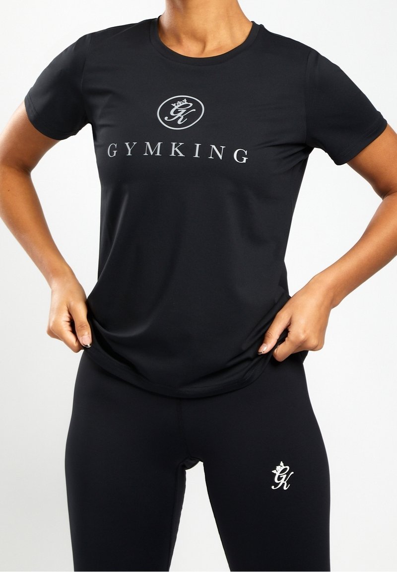 Černé sportovní tričko s krátkým rukávem, se stříbrným logem "GYMKING" a hladkým, elastickým materiálem. V kombinaci s černými legínami.