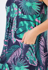 Granatowa sukienka z intensywnymi zielonymi i różowymi wzorami tropikalnych liści. Zawiera marszczony pas i boczne kieszenie. Miękka struktura materiału.