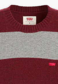 Red and gray striped sweater with a ribbed crew neckline, made of soft knit material. Features a small red logo on the lower right side.