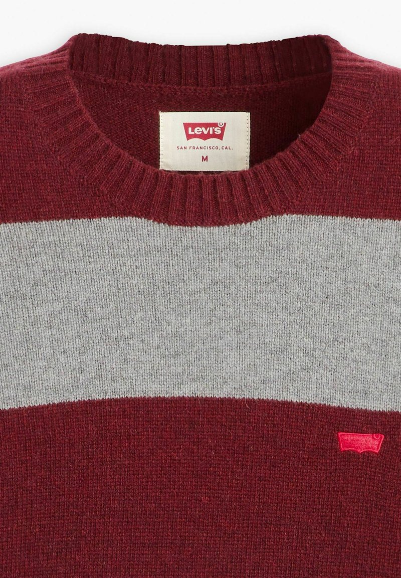Maglione a righe rosse e grigie con scollatura a girocollo a coste, realizzato in morbido materiale knit. Caratterizzato da un piccolo logo rosso sul lato inferiore destro.