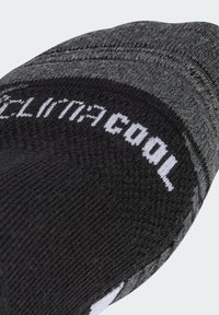 Calcetín negro y gris con tejido texturizado, que presenta un patrón jaspeado. "climacool" está impreso en blanco en la parte superior.