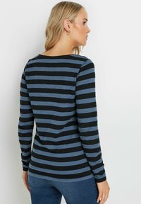 Långärmad topp i svart och blå ränder. Mjuk tyg, rund halsringning och sidsömmar. Kännetecknas av sin vanliga passform och enkla design.