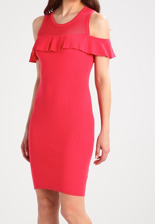 Femme portant une robe rouge sans manches, longueur genou, avec des découpes aux épaules et un détail à volant sur la poitrine.