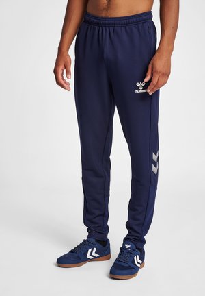 Pantalons de sport bleu marine avec une finition texturée, taille élastique et logo Hummel ; présente des accents latéraux argentés et une coupe droite.