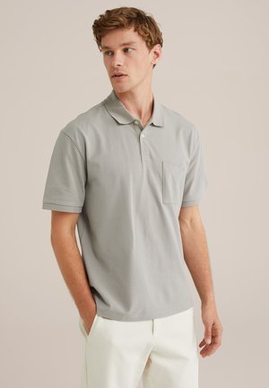 Polo de culoare gri deschis, cu guler, mâneci scurte și un buzunar pe piept. Fabricat din bumbac, având o textură netedă și un design minimalist.