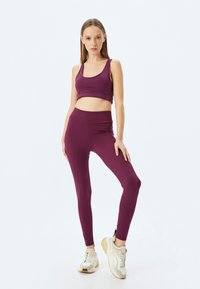 Bordeaux sportbh en legging set. Glad materiaal, aansluitend ontwerp, hoge taille, gecombineerd met beige sneakers. Eenvoudige en functionele sportkleding.