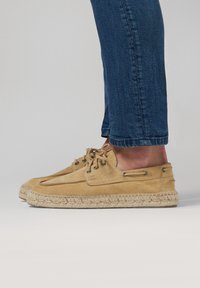 Beige Wildleder-Espadrilleschuhe mit einer strukturierten Oberfläche, ausgestattet mit einer Schnürung, Metallösen und einer gewebten Jutesohle.