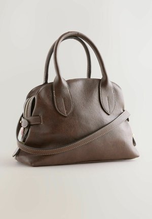 Bolso de mano de cuero marrón con dos asas, una correa de hombro ajustable y cierre de cremallera, con un fondo neutro.