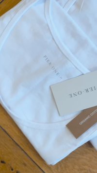 Biały top na ramiączkach z organicznej bawełny z okrągłym dekoltem, z małym nadrukiem logo i metką z napisem "Organic Cotton."