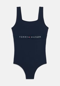 Μαγιό σε ναυτικό μπλε με τετράγωνη λαιμόκοψη και φαρδιές τιράντες, με μια αντίθετη λευκή ταινία με το λογότυπο "TOMMY HILFIGER" γύρω από τη μέση.
