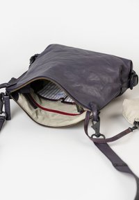 Borsa a tracolla in pelle blu con chiusura a zip, fodera a righe beige e dettagli rossi. Presenta una tracolla regolabile e tasche interne per l'organizzazione.