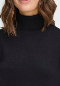 Črni pulover s turtleneck ovratnikom, rebrasto teksturo, prilegajoč design in visoko ovratnico, ki prikazuje gladko, elastično tkanino.