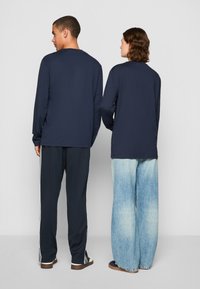 Marineblå langermede skjorter kombinert med mørke bukser og lyseblå vide jeans, med et enkelt, klassisk design og myk stofftekstur.