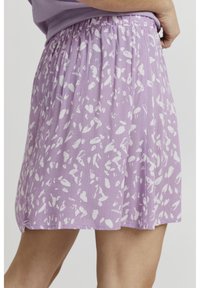 Jupe plissée violette avec un motif abstrait blanc, taille élastique et tissu texturé doux. Longueur mi-cuisse avec une silhouette fluide.