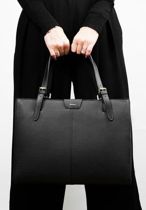 Sac à main en cuir noir avec une surface texturée, deux poignées et un détail en ton doré. Design simple et rectangulaire.