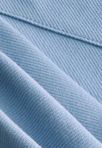 Tela azul con un patrón de tejido diagonal texturizado, que presenta superficies suaves y lisas, y un sutil brillo, dispuesta en suaves pliegues.