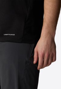 Black short-sleeve shirt with a textured fabric and small white "LIGHTRANGE" logo, shown alongside gray pants and a partially visible hand.
