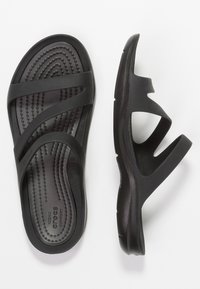 Black rubber sandals with a textured footbed, featuring wide, crossed straps and an ergonomic design for comfort.