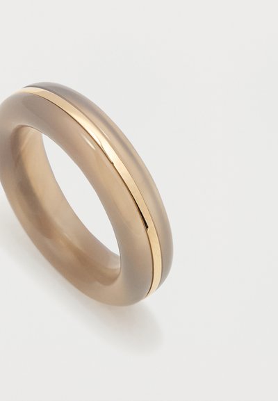Hladký prsteň z taupe živice s tenkým lesklým zlatým kovovým pásikom po celom obvode na bielom pozadí.