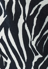 Kankaan zebra-kuvio mustavalkoisena, jossa on rohkeat, aaltoilevat raidat. Teksturoitu pinta, joka näyttää pehmeältä.