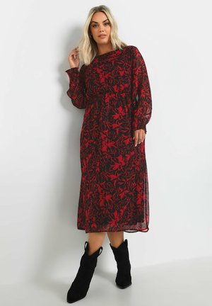 Zwarte jurk met rood bloemenpatroon, semi-doorzichtig materiaal, lange ballonmouwen, een getailleerde taille en een middellange snit, gecombineerd met zwarte enkellaarsjes.