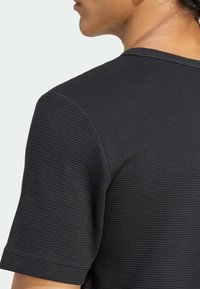 Μαύρο, υφασμάτινο κοντομάνικο πουκάμισο με πλέξη βάφλας, διαθέτει στρογγυλή λαιμόκοψη και καθαρό τελείωμα στις άκρες.