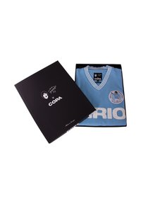 Camiseta azul claro con detalles en blanco y cuello en V, doblada dentro de una caja negra que muestra detalles del diseño gráfico y del logotipo.