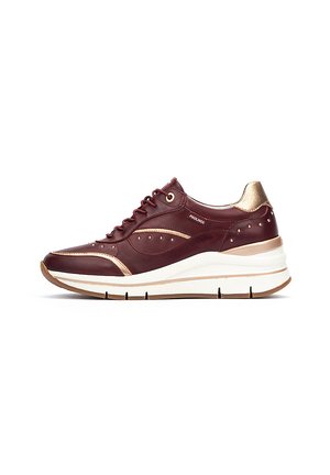 Zapatillas de cuero burdeos con detalles en dorado, perforaciones, diseño de cordones y una suela blanca gruesa con grabado texturizado.