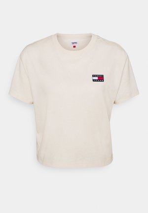 Kort cremet T-shirt med rund hals og et lille Tommy Jeans logo mærke på venstre bryst.