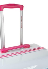 Maleta rígida blanca con acentos rosas, un mango telescópico plateado y un agarre texturizado. Presenta una marca en rosa en el mango.