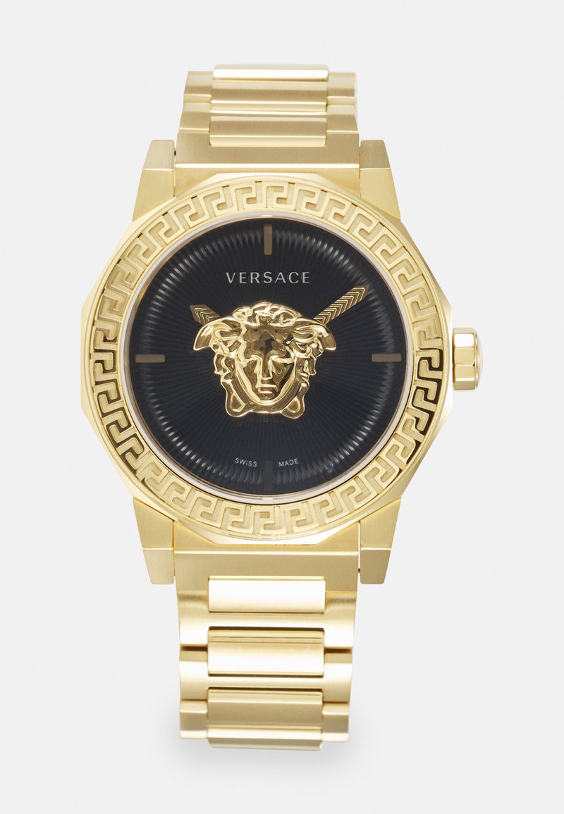 Gold-tone octagonal watch with a black dial, featuring a Medusa emblem and intricate Greek key pattern on the bezel. Swiss made.