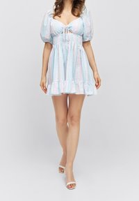 Light blue mini dress with puff sleeves, a tie-front bodice, and ruffled hem. Features pastel vertical stripes and smocked waist.