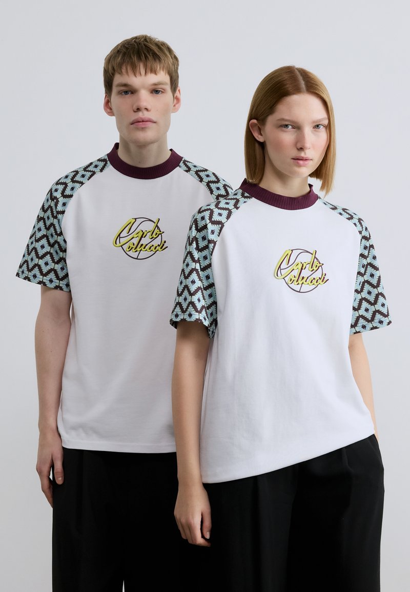 Λευκά T-shirts με κοντά μανίκια σε τυπωμένο σχέδιο σε τιρκουάζ και βουργουνδί, με κυκλικό λογότυπο κεντημένο κίτρινο στο μπροστινό μέρος.