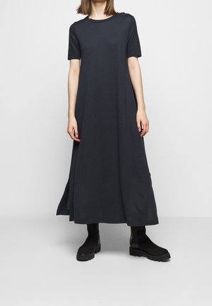 Robe mi-longue bleu marine foncé en coton doux, manches courtes, encolure ronde et fentes latérales ; associée à des bottines noires.