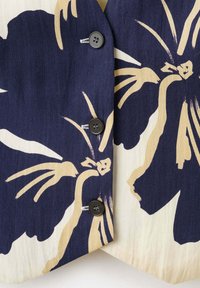 Fabric with large navy and beige floral print, featuring three dark buttons along a vertical seam.