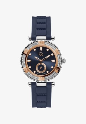 Marineblauwe siliconen horloge met een roestvrijstalen kast, een donkervriendelijke wijzerplaat, rosegouden accenten en een getextureerde bezel met minutenmarkeringen.