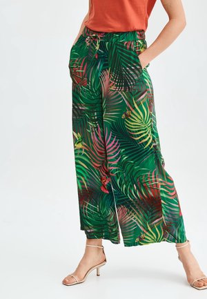 Pantalons larges verts avec des motifs de feuilles vibrants, dotés d'une taille à cordons et de poches. Tissu léger et fluide avec une coupe décontractée.