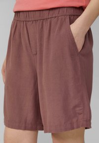 Bordeauxrote Shorts mit einem elastischen Bund, Seitentaschen und einem glatten, leichten Stoff. Flache Nähte und keine sichtbaren Logos.