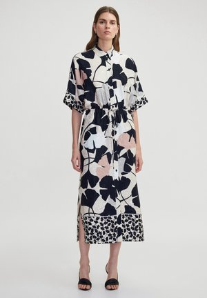 Beige, schwarze und rosa blumengemusterte Hemdkleid mit kurzen Ärmeln, einem Taillengürtel, seitlichen Schlitzen und einem kontrastierenden gemusterten Saum.