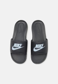 Μαύρα σανδάλια με λslides με υφή στην επάνω και κάτω πλευρά, που διαθέτουν μια φαρδιά λωρίδα με το λογότυπο της Nike σε λευκό και ανοιχτό μπλε.