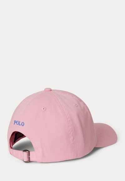 Gorra de béisbol ajustable rosa con bordado azul "POLO" en la parte trasera, hebilla de metal y ojales de ventilación sobre fondo blanco.